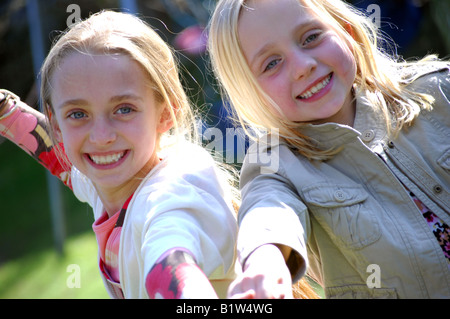 Fotografia delle due sorelle fiducioso giocare felicemente nel loro giardino e sorridente alla fotocamera. Foto Stock