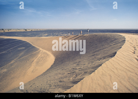 Famiglia caucasica e guida africana a piedi sulla cresta della mezzaluna scolpite di Barchan o trasversale duna di sabbia Kenya Africa orientale Foto Stock