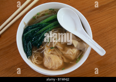 Cina Asia Shanghai zuppa fagottini di canederli in brodo vegetale nella ciotola con il cucchiaio e bastoncini Foto Stock
