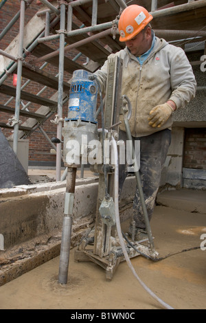 Un builder usa un trapano a percussione durante un edificio di conversione. Foto Stock