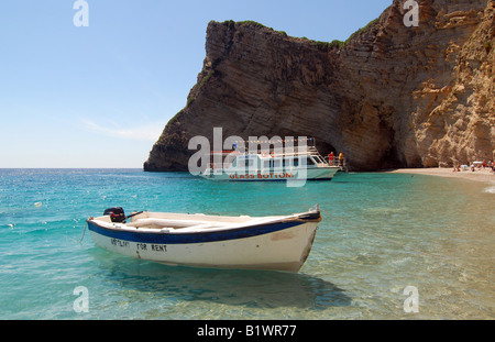 Piccola barca su Paradise Beach, isola greca di Corfù (Mar Ionio). Fondo di vetro per imbarcazione da diporto su sfondo. Foto Stock