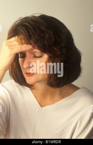 Donna con la sua mano alla sua testa cercando infelice Foto Stock