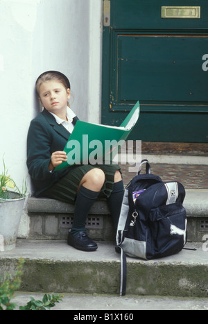 Bambino seduto sulla porta di attesa per i genitori per tornare a casa Foto Stock