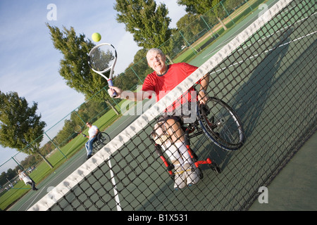 Senior uomo seduto in una sedia a rotelle e giocare a tennis Foto Stock