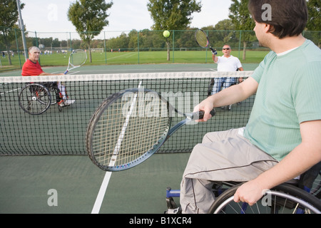 Tre uomini disabili costretti su sedie a rotelle e giocare a tennis Foto Stock