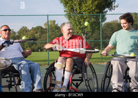Tre uomini disabili costretti su sedie a rotelle e giocare a tennis Foto Stock