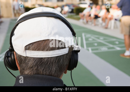 Vista posteriore di un anziano uomo che indossa le cuffie Foto Stock