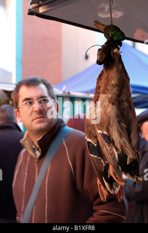 Un passante guarda non impressionati dai prodotti freschi appeso nella parte anteriore di questo macellaio stallo in Dublino. Foto Stock