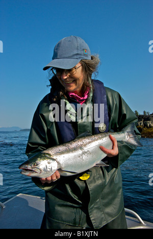 Donna che mantiene un grande BC coho salmoni Pesci a isole nodose in British Columbia settentrionale pescati troll la pesca Foto Stock