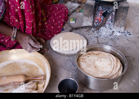 Una madre di Rajasthan deserto di Thar India prepara chapati un fiocco focaccia di azzimo pasta cotta tipo di roti. Foto Stock