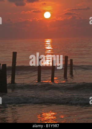Tramonto sull'Oceano Atlantico con onde e pontili in legno Foto Stock