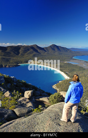 Un scalatore guarda giù su Wineglass Bay, Tasmania, dalla cima del monte Amos. Foto Stock