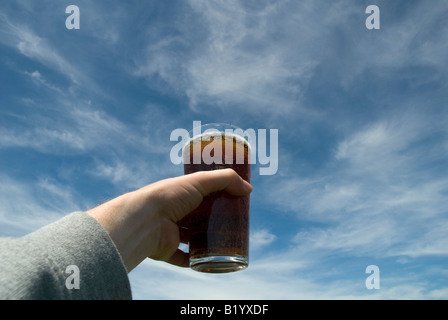 Con in mano una pinta di bitter contro un cielo blu Foto Stock