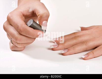 Close up di un signore mani chiara applicazione di smalto per le unghie al suo unghie finte Foto Stock