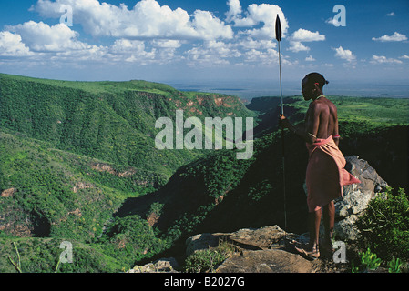 Samburu guerriero o moran in abito tradizionale armati di lancia guardando giù il El Kajarta Gorge dal Monte Kulal nel nord del Kenya Foto Stock