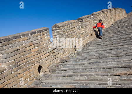 Chinese Boy salire a piedi a gradini della Grande Muraglia a Mutianyu a nord di Pechino CINA Foto Stock