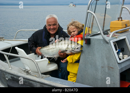 Piccolo Ragazzo e uomo azienda big British Columbia chinook re salmone pescato pesca troll Foto Stock