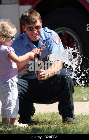 Un vigile del fuoco e una giovane ragazza utilizzando una manichetta  antincendio Foto stock - Alamy