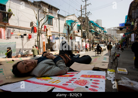 Uomo dorme sul cartone in Zi Zhong Road vecchia Shanghai in Cina Foto Stock