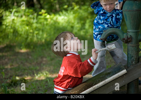 Michigan Prairieville fratelli di 2 e 4 anni la vecchia pompa acqua con un esterno di pompa a mano Foto Stock