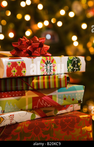 Natale pila di scatole confezionate impilati vicino decorate e albero di Natale illuminato presenta con archetti carta di avvolgimento Foto Stock