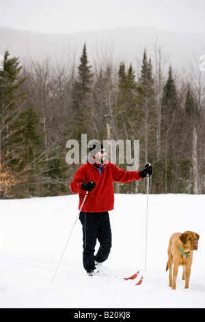 Un uomo lo sci di fondo con il suo cane sul Catamount Trail in Stowe, Vermont. Foto Stock