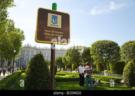 Spagna Madrid due uomini con i cani al guinzaglio in giardini di Plaza de Oriente vicino Palazzo Reale segno in Spagnolo Inglese Foto Stock