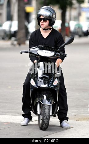 Un giovane uomo elegante si siede sul suo scooter/ciclomotore su una calda sera d'estate in Place de la Bastille a Parigi. Foto Stock