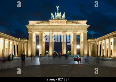 Una vista di turisti scattare fotografie al Brandenburger Tor o Porta di Brandeburgo al tramonto di sera. Foto Stock