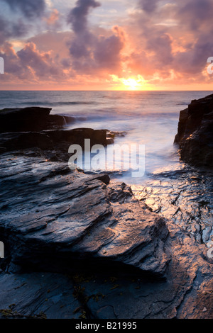 Tramonto scende all'orizzonte dietro Trebarwith Strand Cornwall Inghilterra Foto Stock