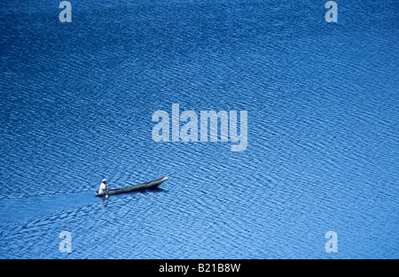 Un solitario solitario uomo locale in un ceppo di legno piroga paddeling sul lago Bunyonyi e. Foto Stock