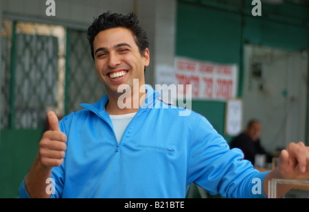 Un mercato Trader fornisce un 'pollice in alto" per la fotocamera in Schunat HaTikvah (quartiere di Speranza) di Tel Aviv, Israele. Foto Stock