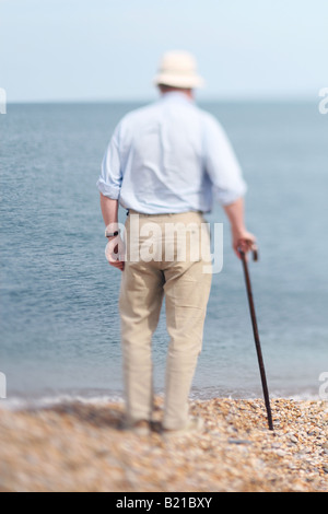 Uomo anziano con il bastone da passeggio si fermò sulla spiaggia Foto Stock