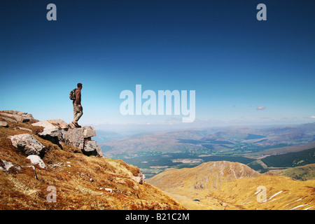 Uomo in piedi alla cima della montagna guardando la vista Foto Stock