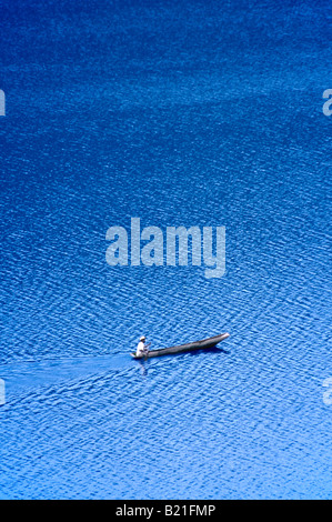 Un solitario solitario uomo locale in un ceppo di legno piroga paddeling sul lago Bunyonyi e. Foto Stock