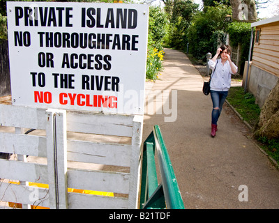 Giovane donna cammina verso un isola privata segno all'ingresso pedonale punto di anguilla isola a torta, Twickenham, Inghilterra Foto Stock