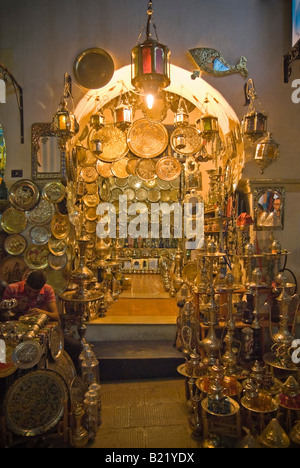 Verticale tempo di notte vista al di fuori di un tradizionale tunisino negozio di lamiera piena di piastre di ottone, teiere e lanterne Foto Stock