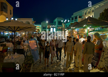 Orizzontale di ampio angolo di turisti a piedi attorno a artigianato tradizionale con bancarelle e negozi all'interno della Medina di notte. Foto Stock