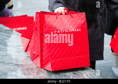 Red Christmas shopping bags di FAO Schwarz toy store sulla Fifth Avenue di Manhattan a New York City USA Foto Stock