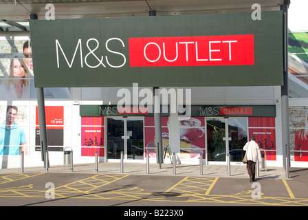 M&S outlet store e logo presso Junction Retail Park, modello con vista posteriore rilasciato, donna che acquista in procinto di entrare nel negozio a Thurrock Essex Inghilterra, Regno Unito Foto Stock