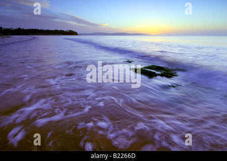 La rottura dell'alba sulla foreshore a Goodrington Sands nel South Devon con l'alba luce riflettendo sulle onde Foto Stock