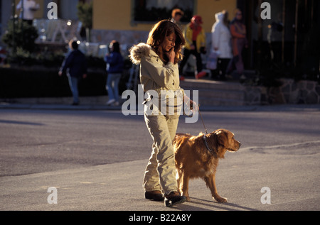 Donna cane passeggiando attraverso Cortina d Ampezzo Dolomiti Italia Foto Stock