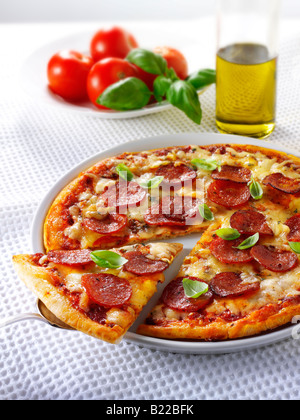 Pizza e rabboccato con salsiccia per pizza, basilico con una fetta fuori Foto Stock