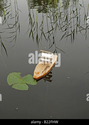 Un po' di nave a vela a mano sul lago con ninfee e canneti Foto Stock