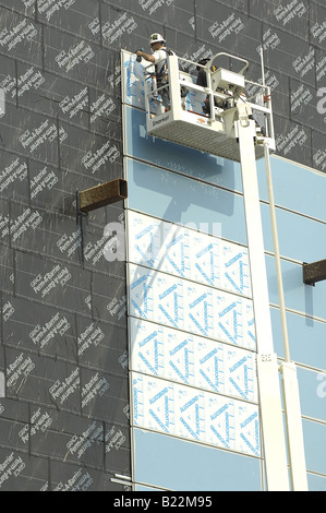 Lavoratori su un elevato uomo sollevare installare pannelli esterni su pannelli di isolamento su un edificio di recente costruzione a Los Angeles, C Foto Stock