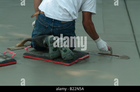 Workman livellamento di calcestruzzo bagnato con un Darby durante la costruzione di una strada di fronte a una casa privata in California. Foto Stock