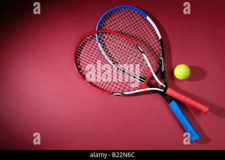 Racchette da tennis e una sfera isolata su sfondo rosso Foto Stock