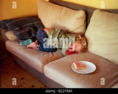 4 anno vecchio ragazzo si addormenta sul divano dopo un pasto di mezzogiorno Foto Stock