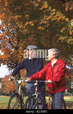 Coppia senior a piedi con le biciclette in posizione di parcheggio Foto Stock