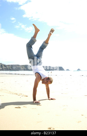 L'uomo facendo handstand sulla spiaggia Foto Stock